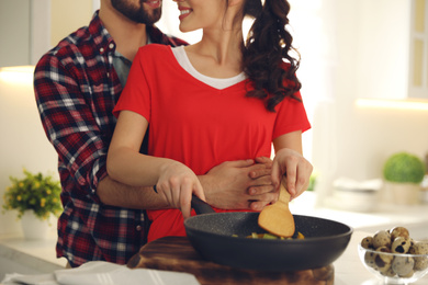 Photo of Lovely young couple cooking together in kitchen, closeup