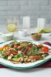 Delicious salad with beef tongue, grilled vegetables, peach, blue cheese and fork served on white table