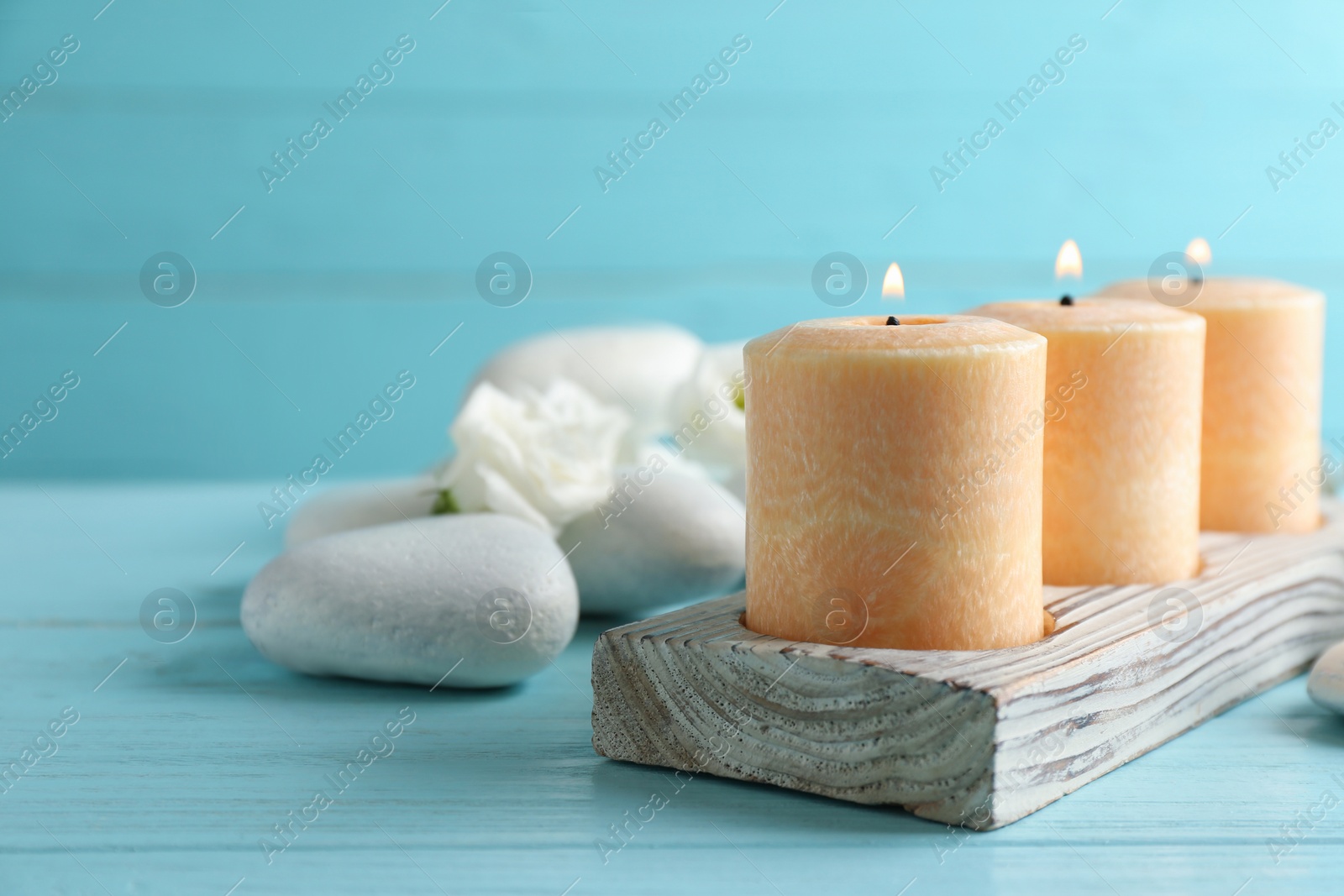 Photo of Composition with burning candles, spa stones and flowers on table. Space for text