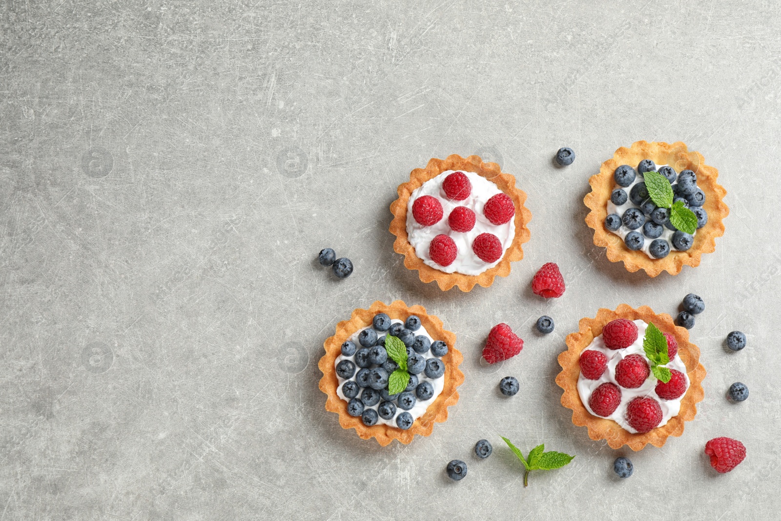 Photo of Delicious sweet pastries with berries on grey table, flat lay. Space for text