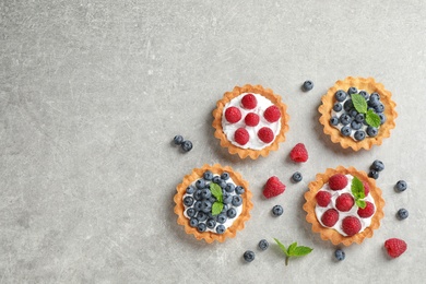 Photo of Delicious sweet pastries with berries on grey table, flat lay. Space for text