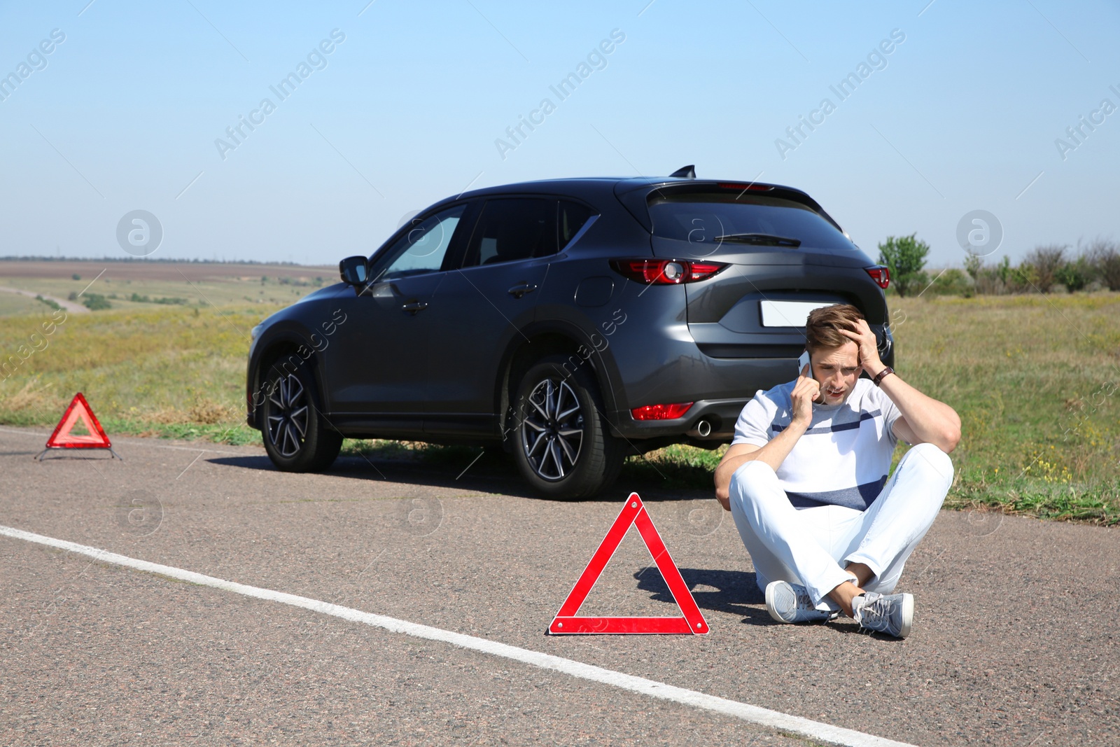 Photo of Man talking on phone near broken car outdoors