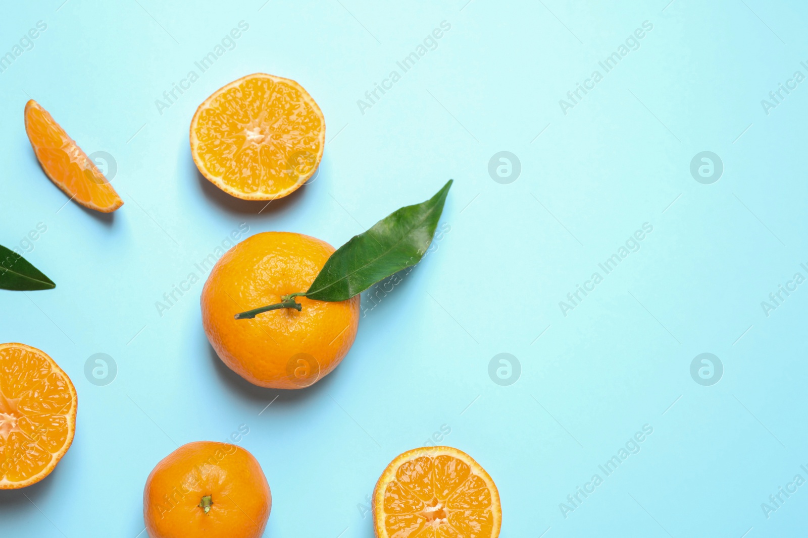 Photo of Flat lay composition with fresh ripe tangerines and leaves on light blue background, space for text. Citrus fruit