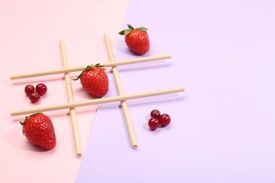 Photo of Tic tac toe game made with berries on color background. Space for text