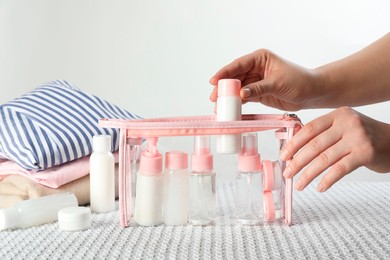 Woman putting small bottle with personal care product into plastic bag, closeup. Cosmetic travel kit