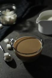 Photo of Tasty coffee with milk in cup and sugar cubes on grey table, closeup