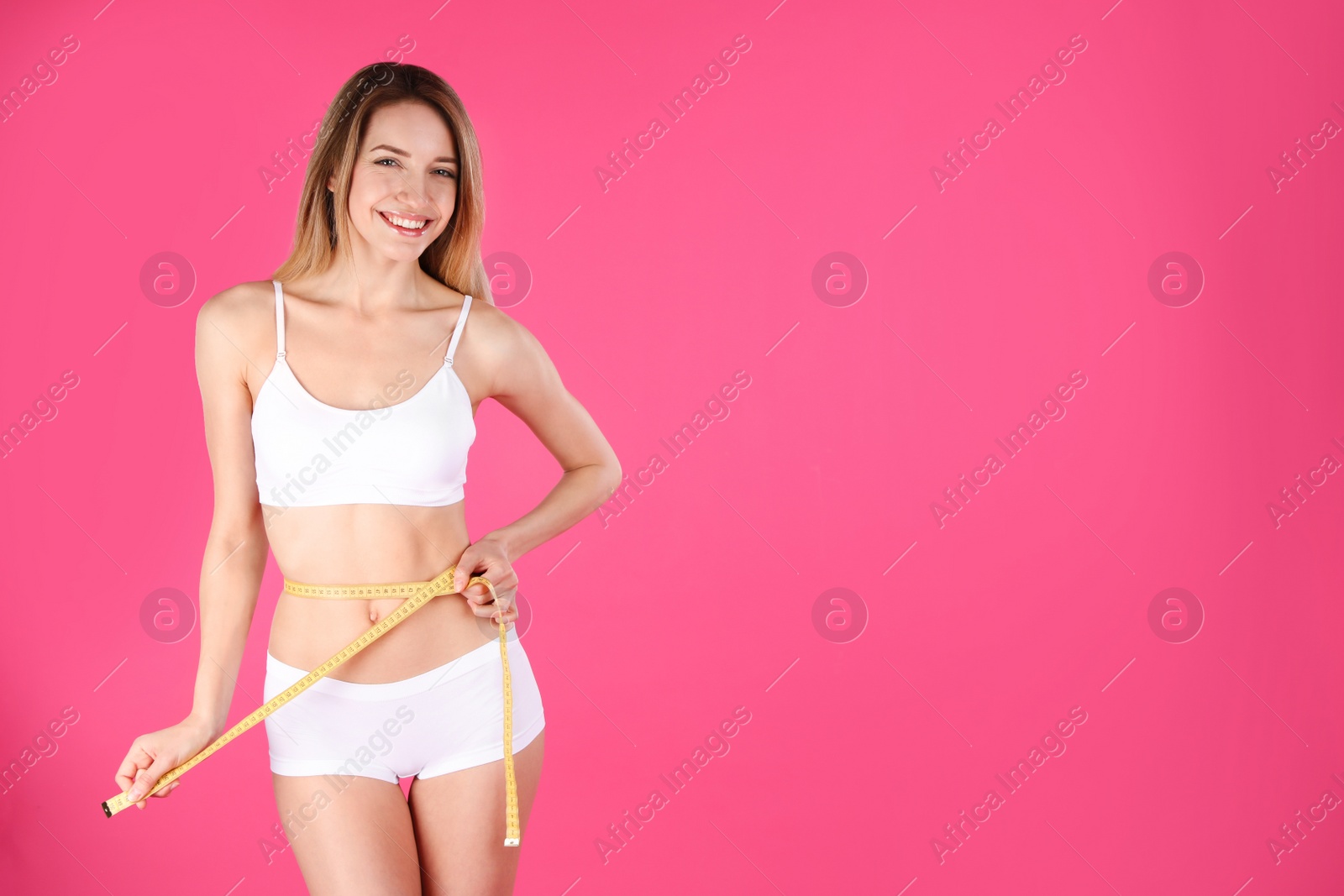 Photo of Slim woman measuring her waist on color background, space for text. Perfect body