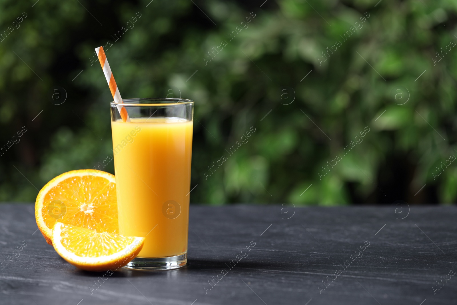 Photo of Glass of orange juice and fresh fruits on grey table. Space for text