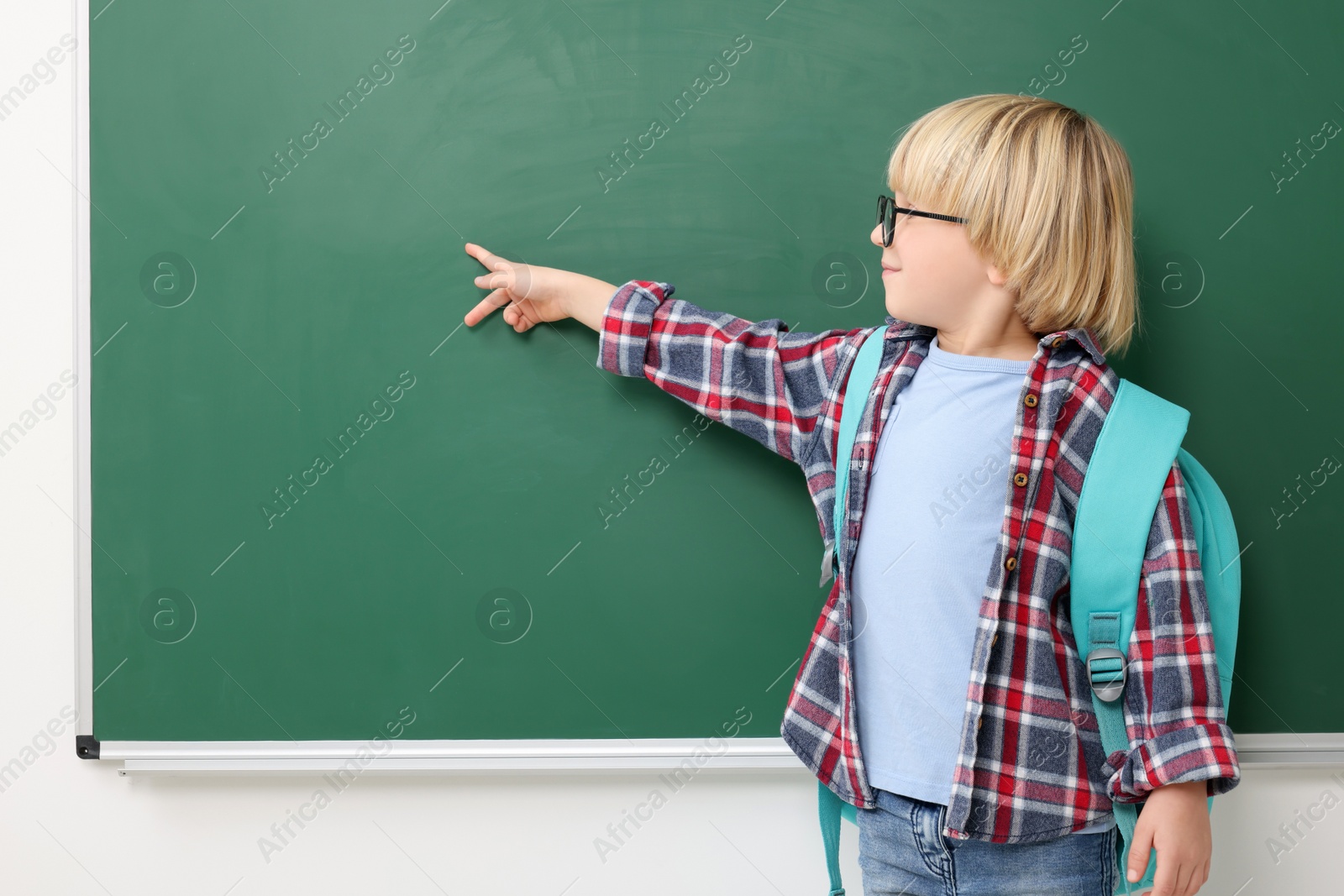 Photo of Little school child pointing at chalkboard. Space for text