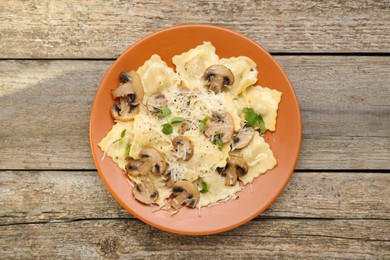 Photo of Delicious ravioli with mushrooms and cheese on wooden table, top view