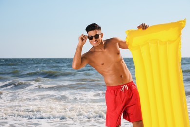 Photo of Man with yellow inflatable mattress at beach