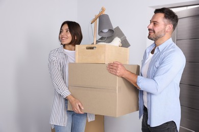 Photo of Happy couple with moving boxes entering in new apartment