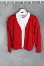 Photo of Shirt and jumper hanging on blue wall. School uniform