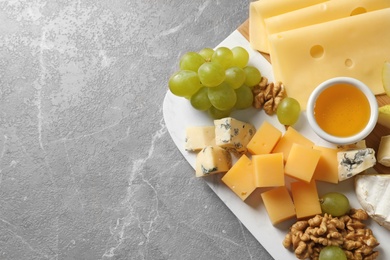 Board with different kinds of delicious cheese and snacks on marble background, top view. Space for text