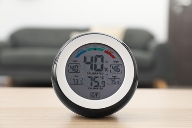 Photo of Digital hygrometer with thermometer on wooden table in room, closeup