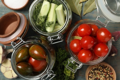 Photo of Pickling jars with fresh ripe vegetables and spices on blue wooden table, flat lay