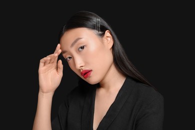 Portrait of beautiful young Asian woman on black background