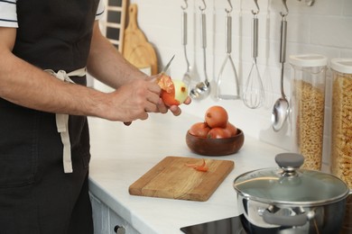 Photo of Man peeling onion at kitchen counter, closeup. Preparing vegetable