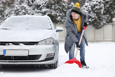 Photo of Man removing snow with shovel near car outdoors