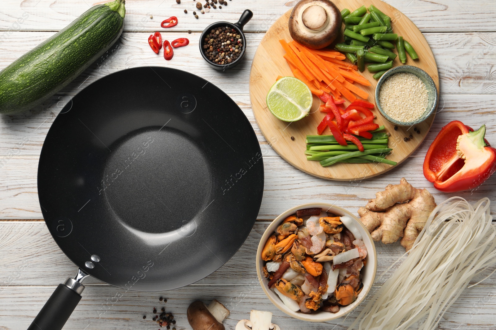 Photo of Flat lay composition with black wok and products on light wooden table