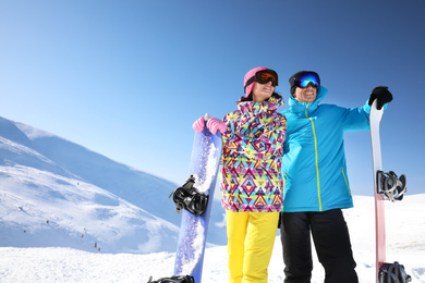 Couple with snowboards on hill, space for text. Winter vacation