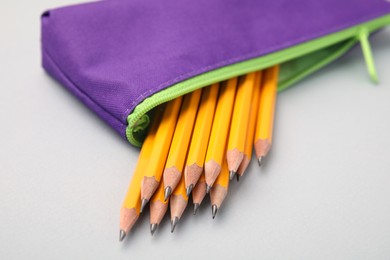 Many sharp pencils in pencil case on light grey background, closeup