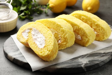 Delicious cake roll with cream filling on grey table, closeup