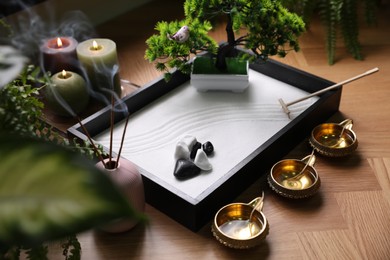 Photo of Beautiful miniature zen garden, incense sticks and oil lamps on table