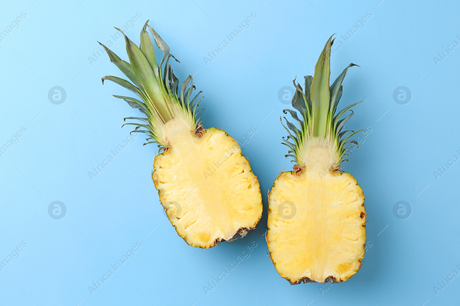 Photo of Fresh pineapple halves on color background