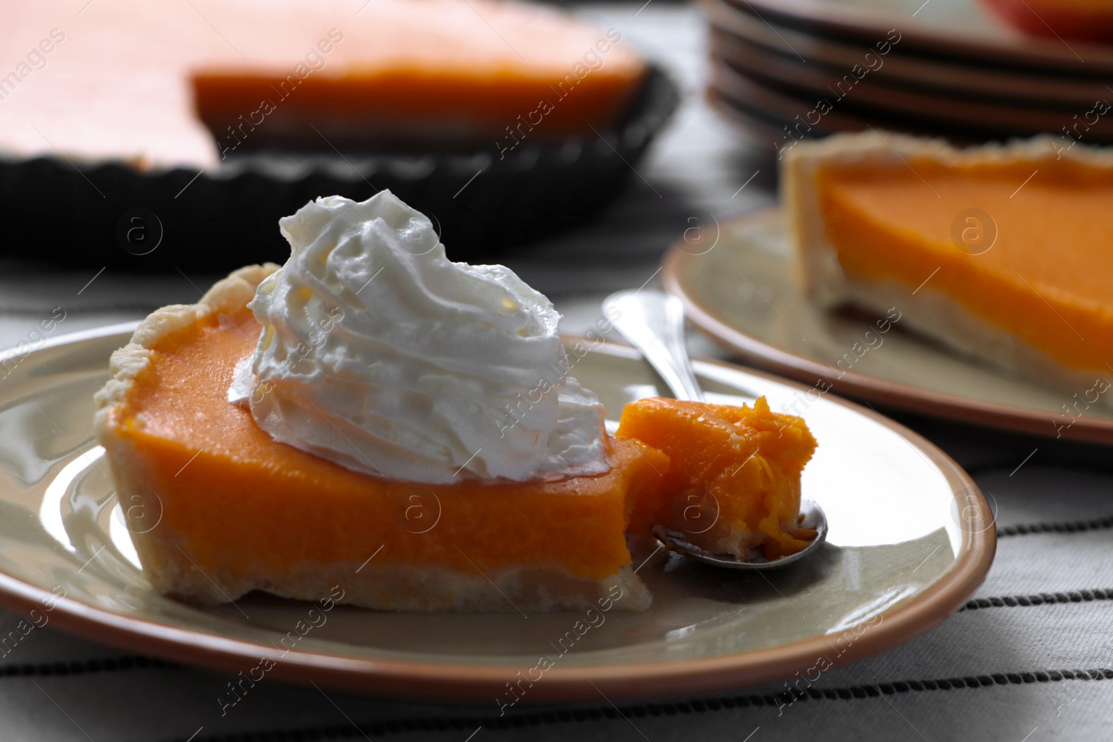 Photo of Piece of fresh homemade pumpkin pie with whipped cream on table