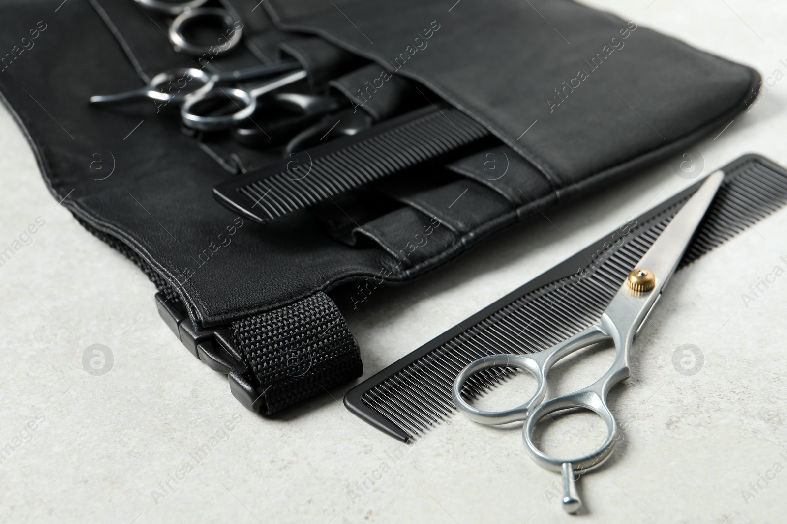 Photo of Hairdresser tools. Professional scissors and combs in leather organizer on white table, closeup