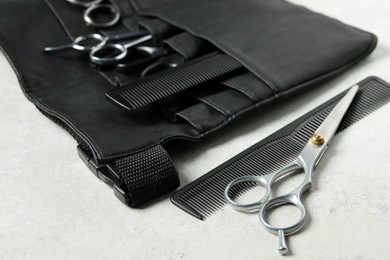 Photo of Hairdresser tools. Professional scissors and combs in leather organizer on white table, closeup