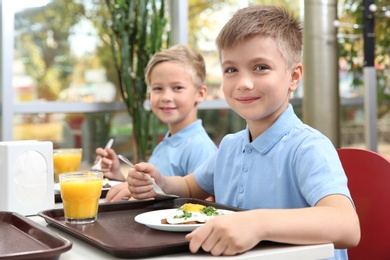Cute children at table with healthy food in school canteen