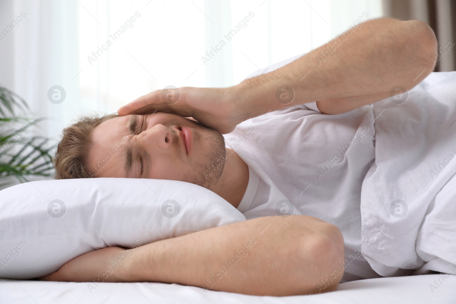 Photo of Handsome young man lying under blanket at home. Bedtime