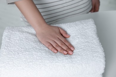 Photo of Woman touching soft white towel indoors, closeup