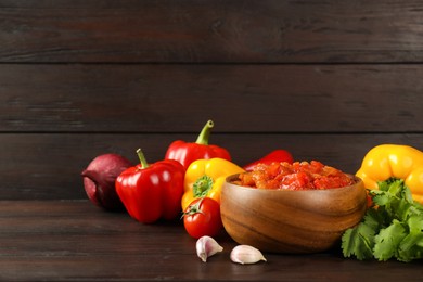 Photo of Tasty lecho and fresh ingredients on wooden table. Space for text