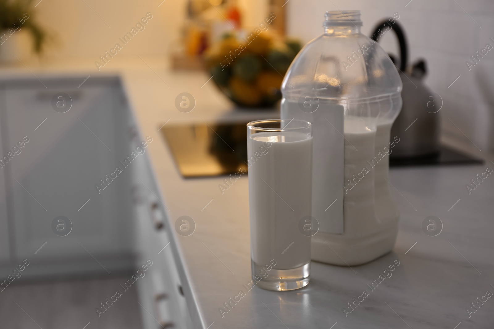 Photo of Gallon bottle of milk and glass on white countertop in kitchen. Space for text