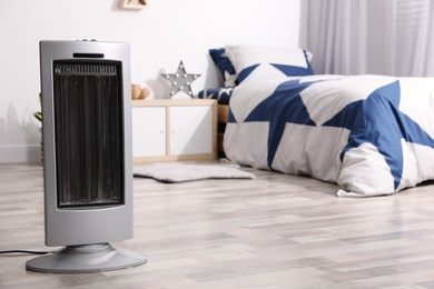 Photo of Modern electric heater on floor at home. Space for text