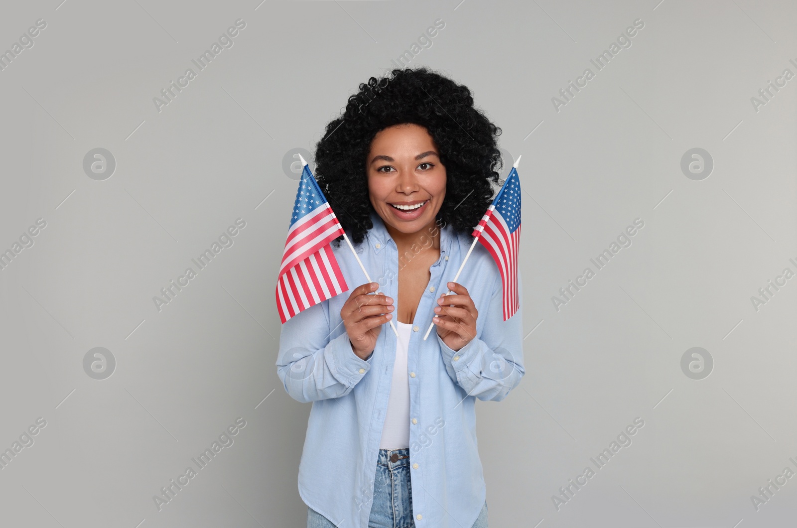 Photo of 4th of July - Independence Day of USA. Happy woman with American flags on light grey background