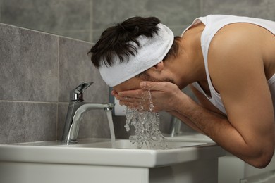 Photo of Man with headband washing his face in bathroom