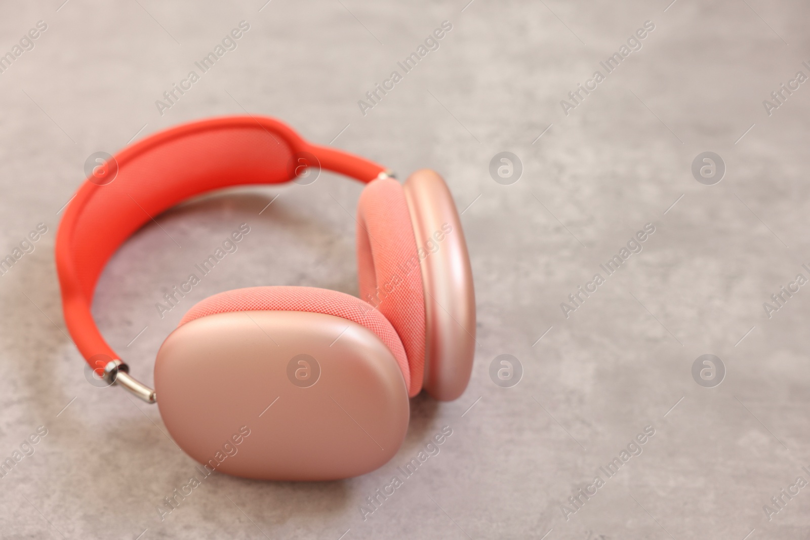 Photo of Stylish pink headphones on light grey table, closeup. Space for text