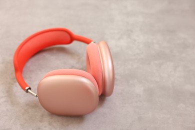 Photo of Stylish pink headphones on light grey table, closeup. Space for text