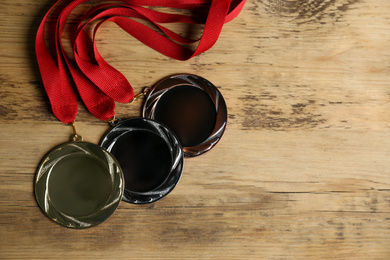 Gold, silver and bronze medals on wooden background, flat lay. Space for design