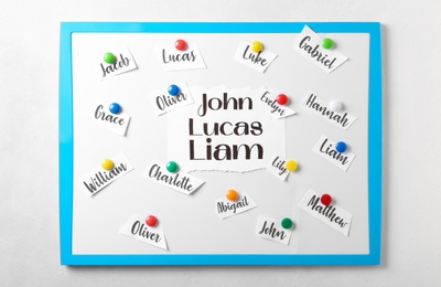 Board with baby names hanging on white wall