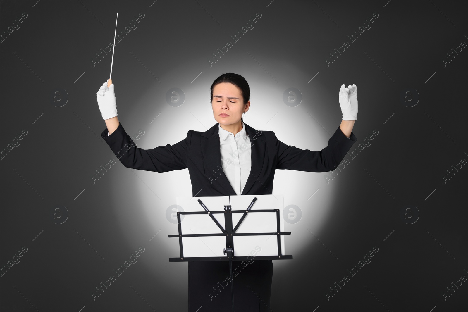 Photo of Professional conductor with baton and note stand on grey background