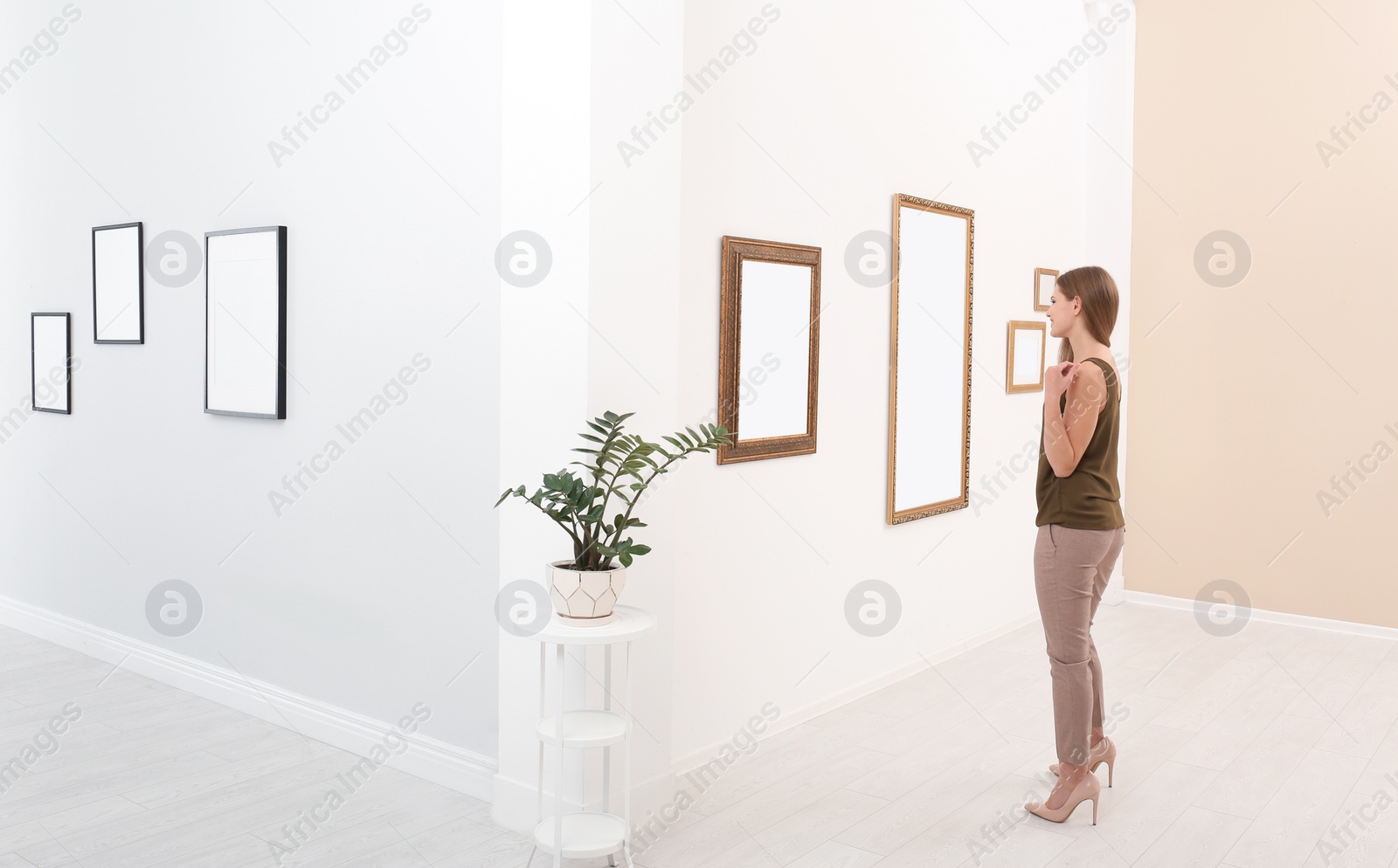 Photo of Young woman viewing exposition in modern art gallery