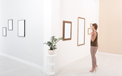 Photo of Young woman viewing exposition in modern art gallery