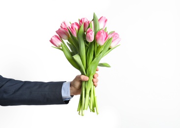 Photo of Man holding bouquet of beautiful spring tulips on light background, closeup. International Women's Day