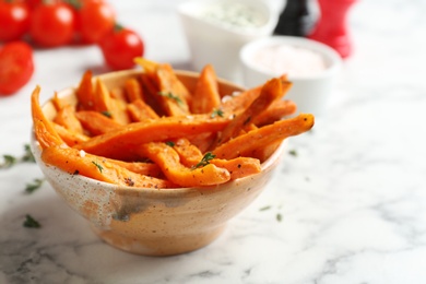 Bowl with sweet potato fries on marble table, space for text