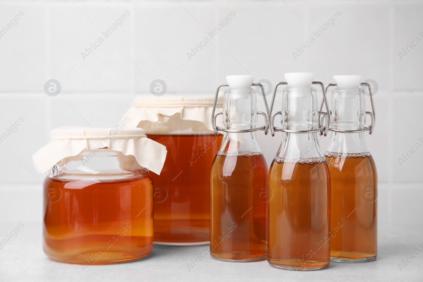 Photo of Tasty kombucha in glass jars and bottles on white table